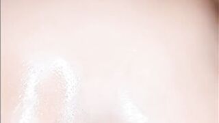 Afro woman oiling her large breasts and groaning