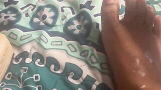 Black playgirl rubbing oil on her feet
