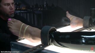 Chained and lied on her back in latex costume black serf Daisy Ducati gets feet tormented then spanked and whipped and anal fingered by slaver The Pope